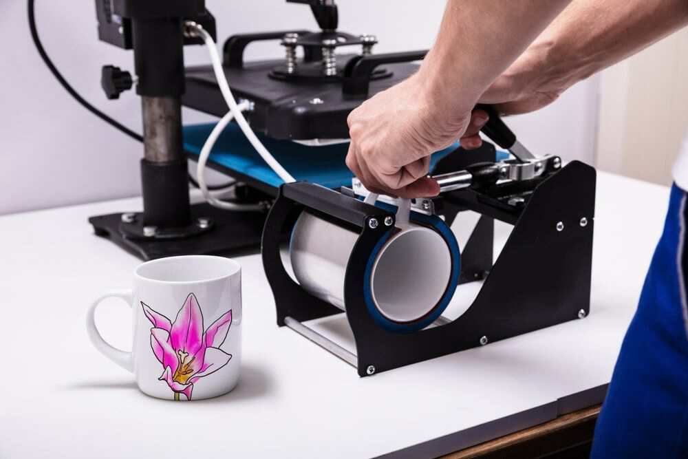 a person printing flower design on mugs