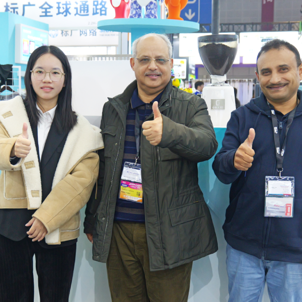 Group photo of staff and clients at DTF printer booth holding printed textile samples.